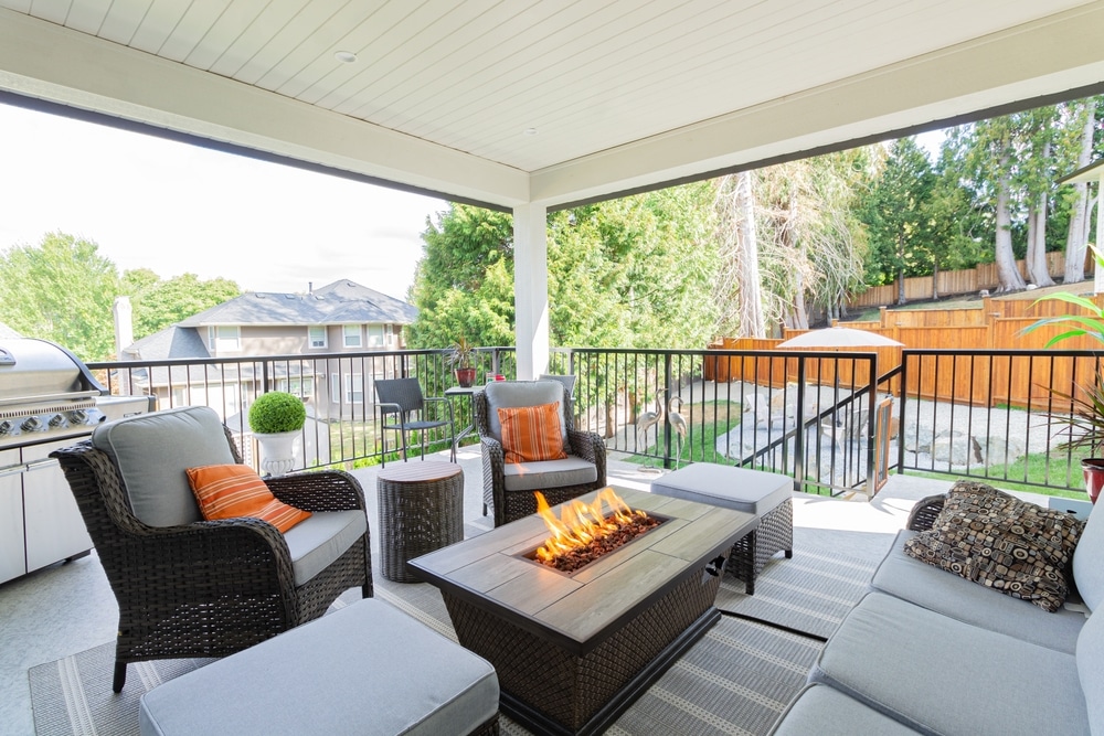 A luxurious spacious deck with stylish patio furniture with a fire pit table heater